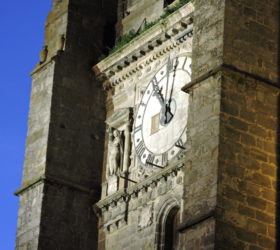 L'horloge de l'église St-Denis flanquée d'une statuette de pierre